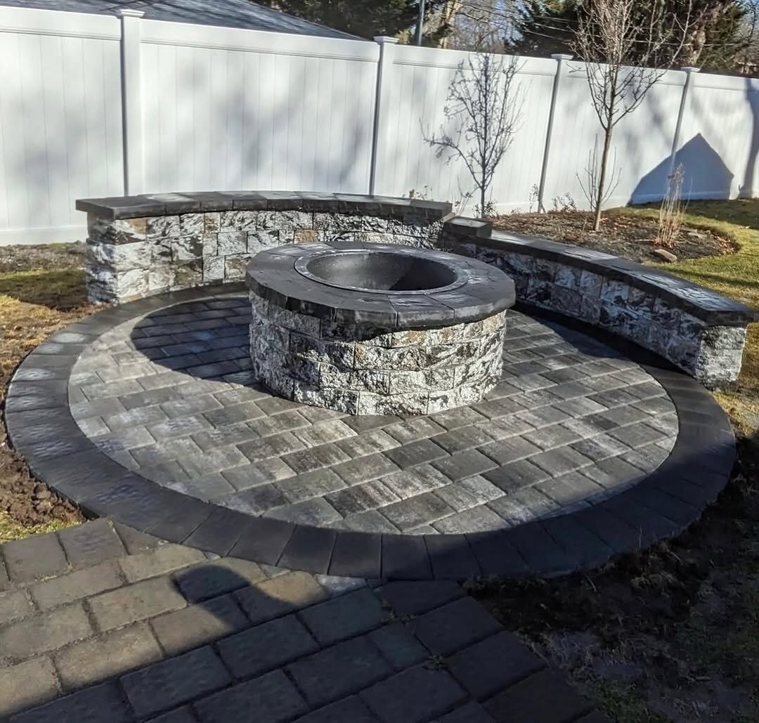 Backyard fire pit with curved paver patio and seating wall