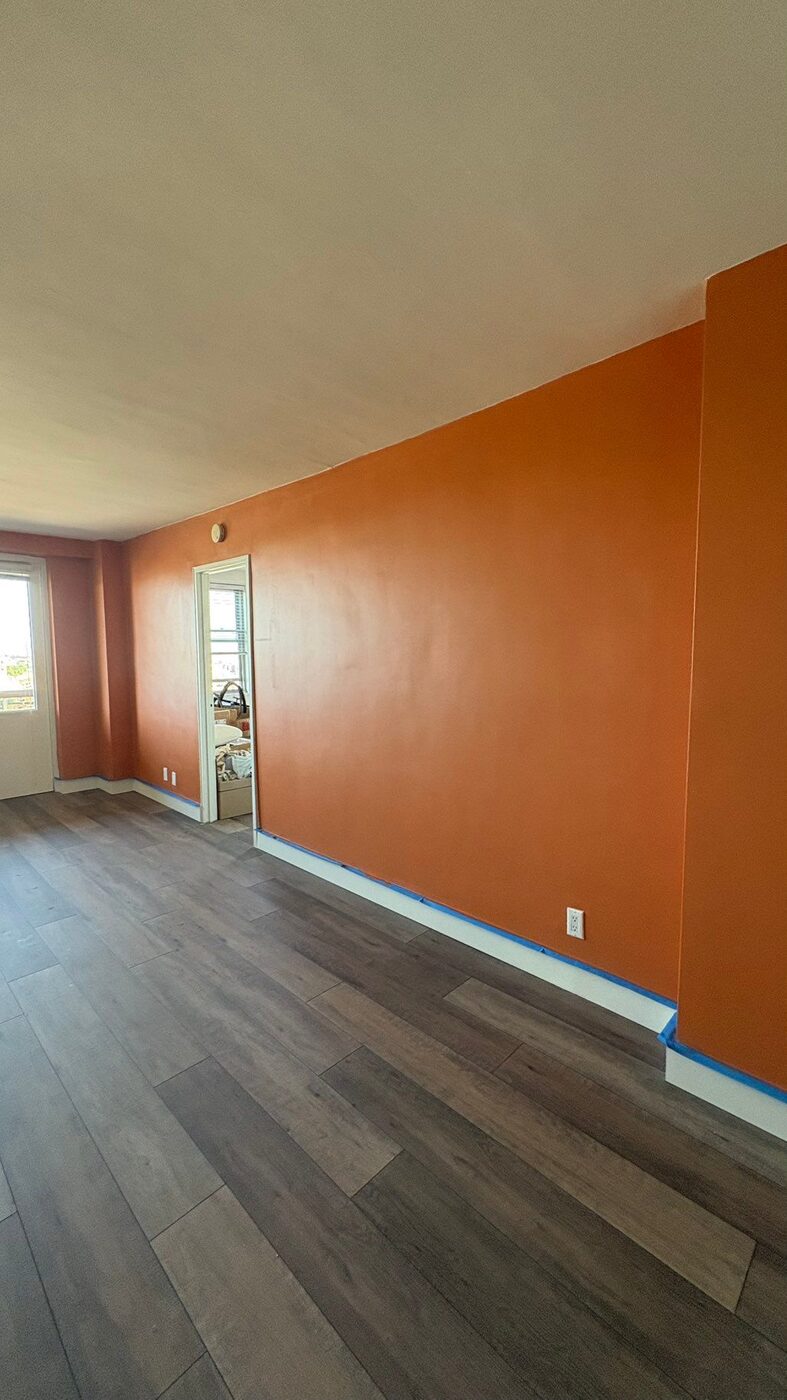 Living room with burnt orange accent wall and new flooring